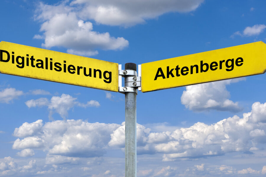 Zwei gelbe Wegweiser mit den Aufschriften "Digitalisierung" und "Aktenberge".