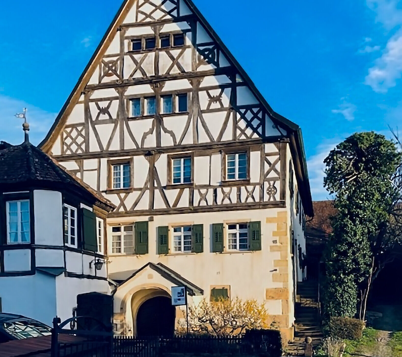 Fachwerkhaus mit grün-weißen Fensterläden, blauer Himmel im Hintergrund.