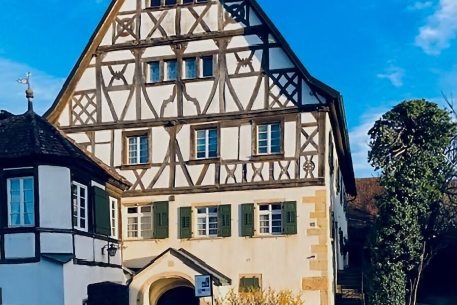 Fachwerkhaus mit grün-weißen Fensterläden, blauer Himmel im Hintergrund.