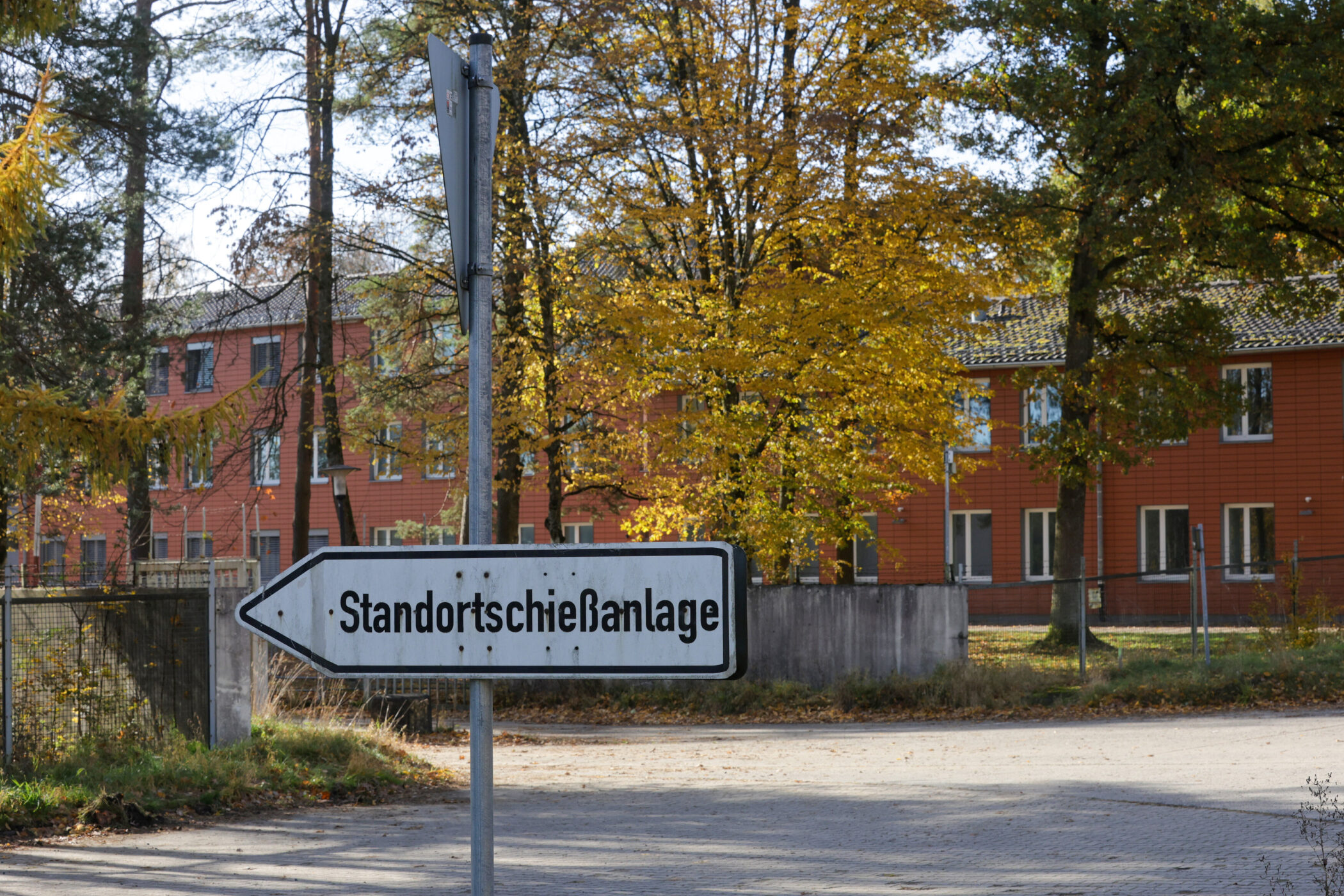 Schild mit Aufschrift "Standortschießanlage", Gebäude und Bäume im Hintergrund.