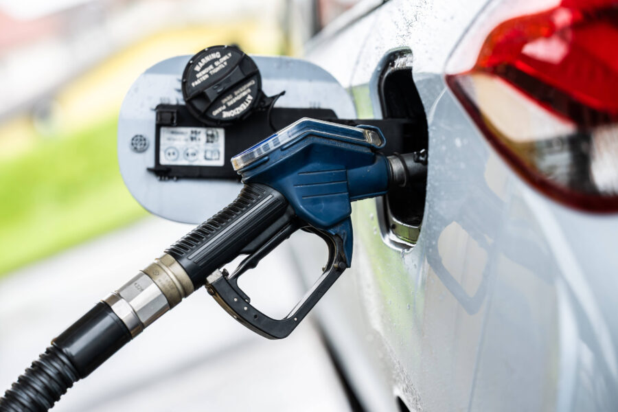 Zapfpistole in einem Autotankstutzen, Tankdeckel geöffnet.