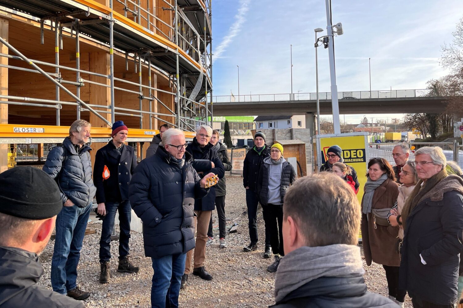 Gruppe von Menschen steht vor einem Gebäude mit Gerüst.