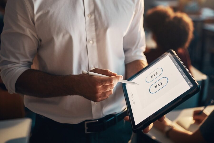 Person hält Tablet mit Stift, zeigt auf Bildschirm mit Tasten F13 und F11.
