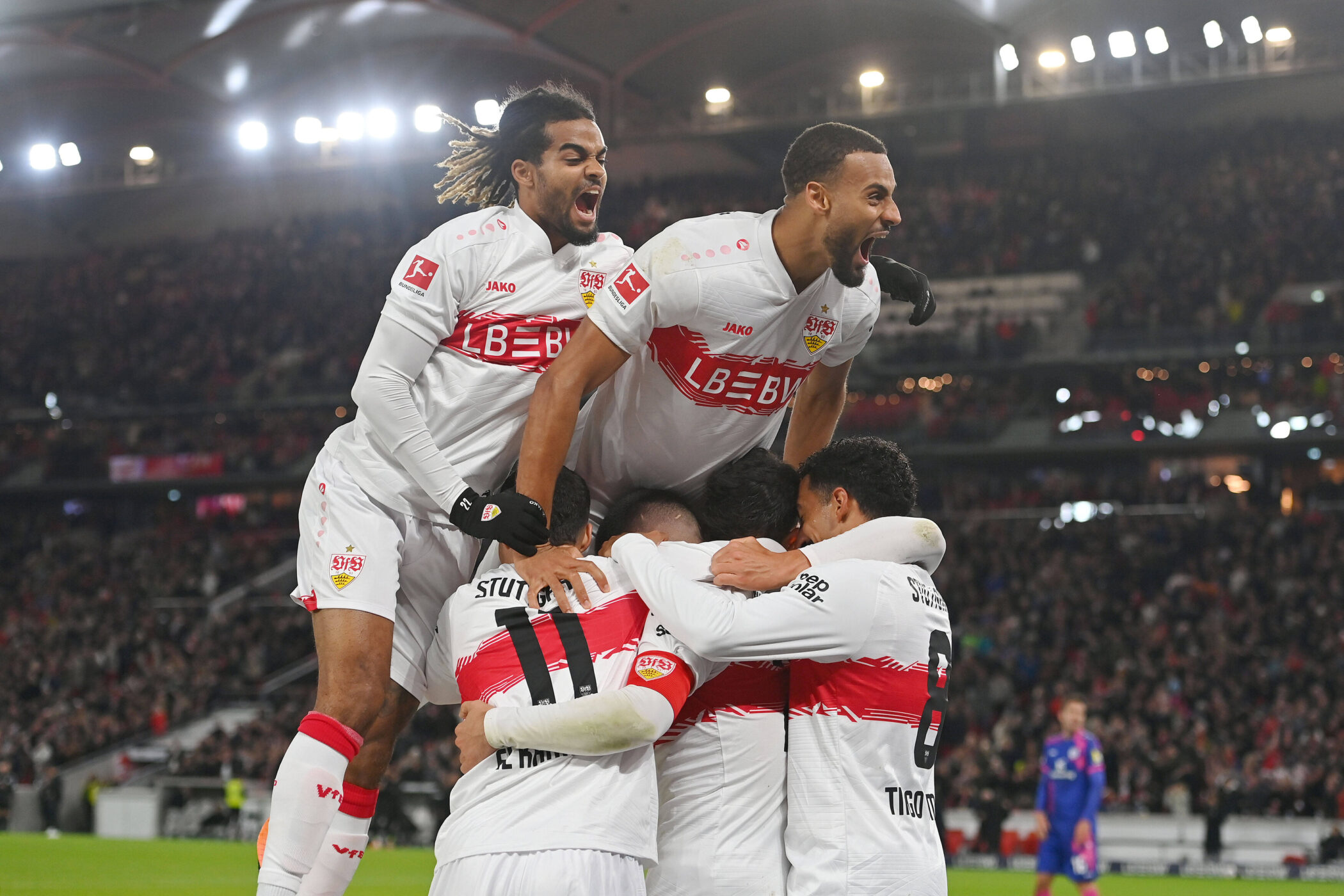 Fußballspieler in weißen Trikots jubeln im Stadion.