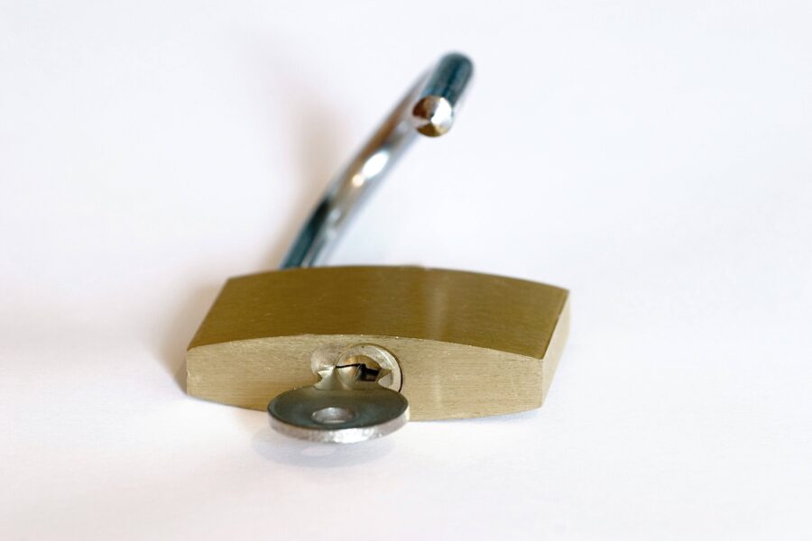 Offenes Vorhängeschloss mit eingestecktem Schlüssel auf weißem Hintergrund.