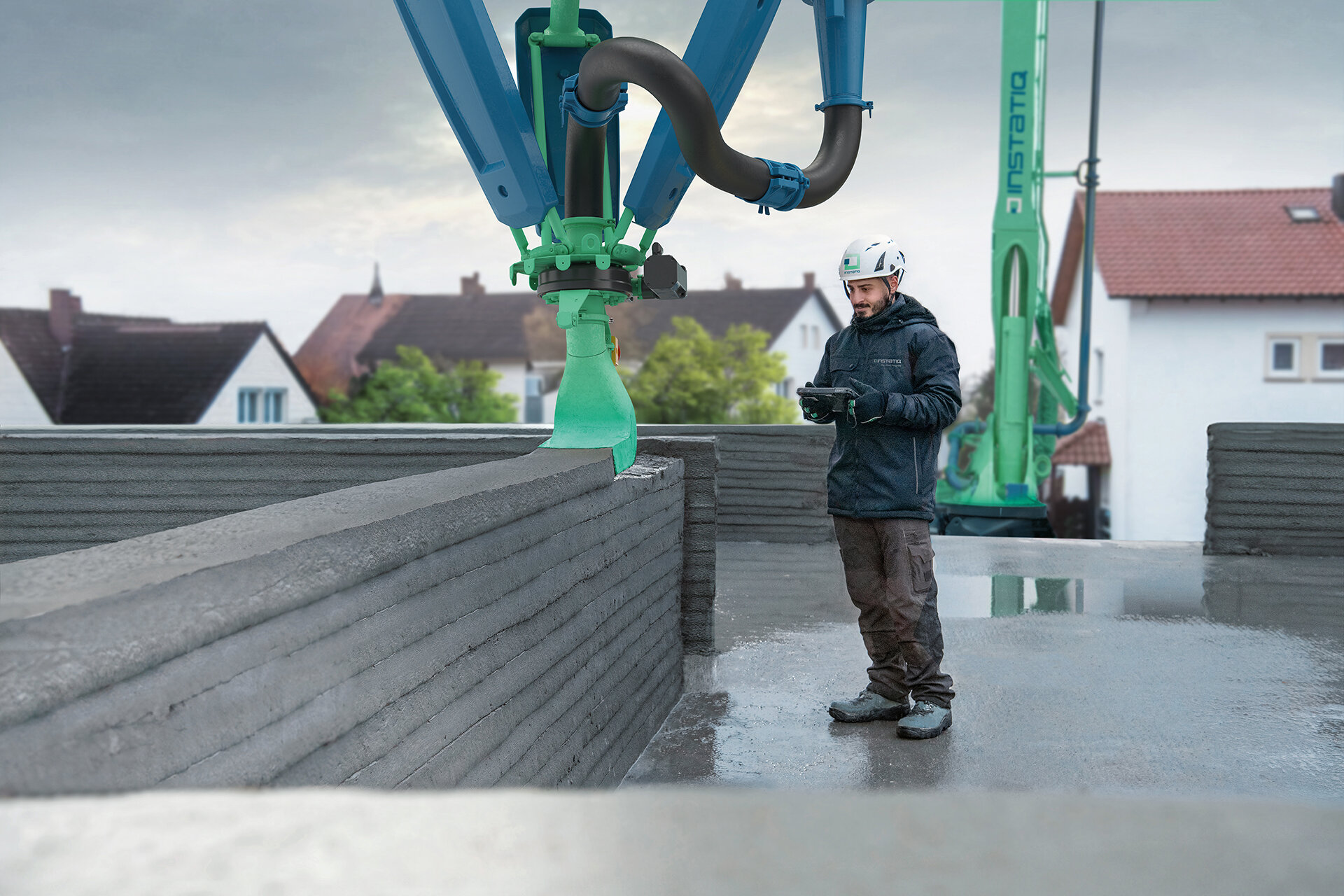 Person mit Helm bedient Maschine auf Baustelle, die Betonwände druckt.