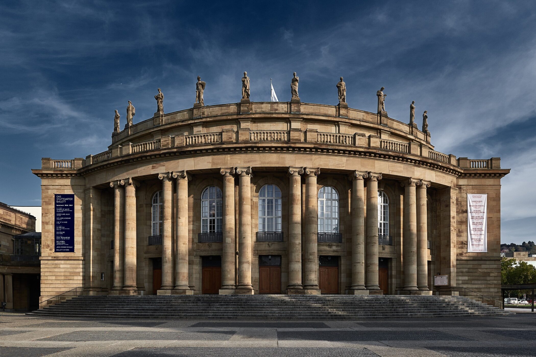 Rundes Gebäude mit Säulen und Statuen, zwei große Banner an den Seiten.