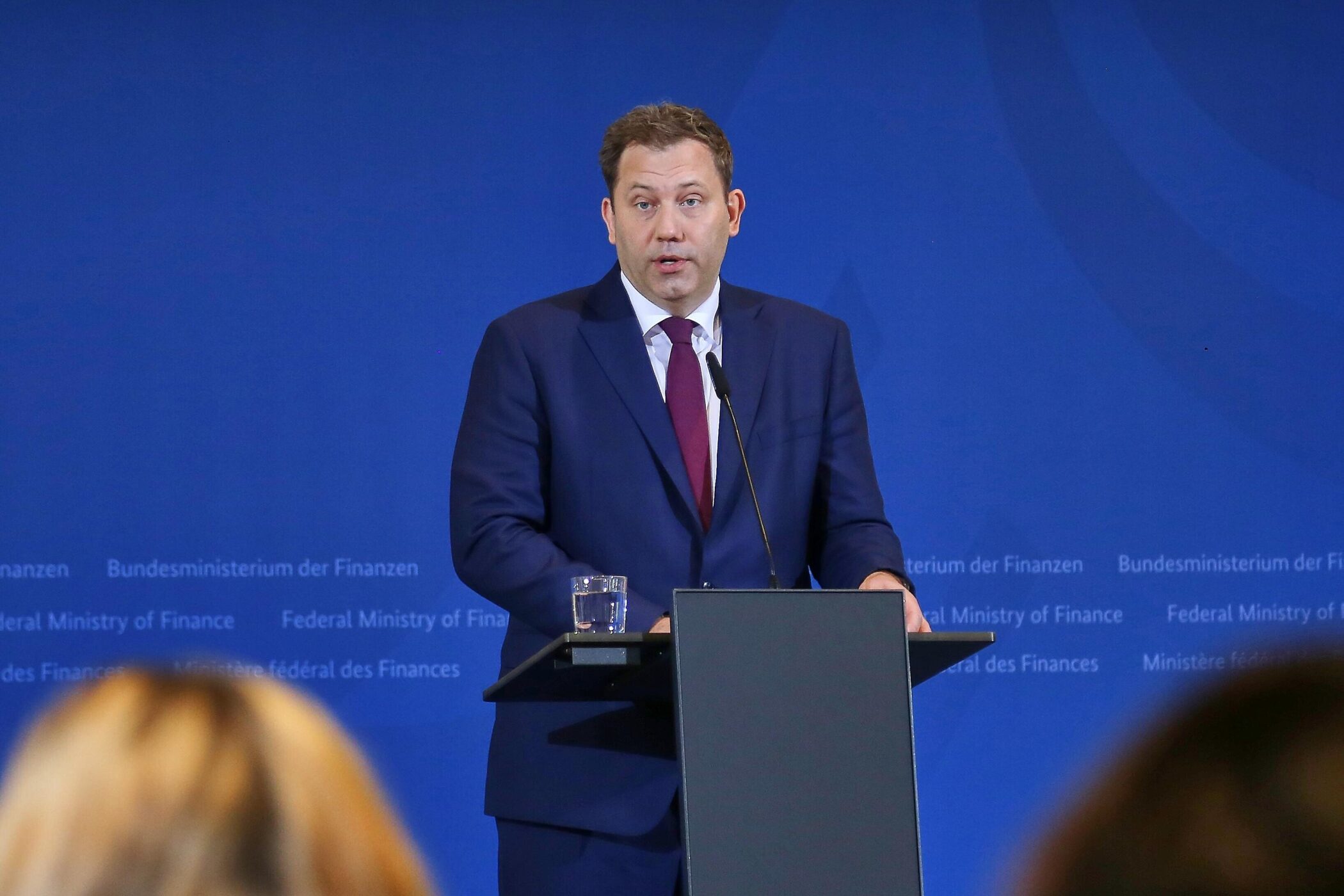 Mann im Anzug spricht am Rednerpult vor blauer Wand mit Text "Bundesministerium der Finanzen".