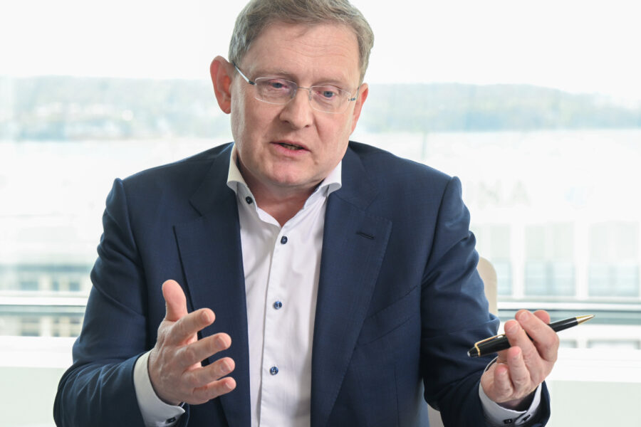 Mann im Anzug spricht gestikulierend, hält einen Stift in der Hand.