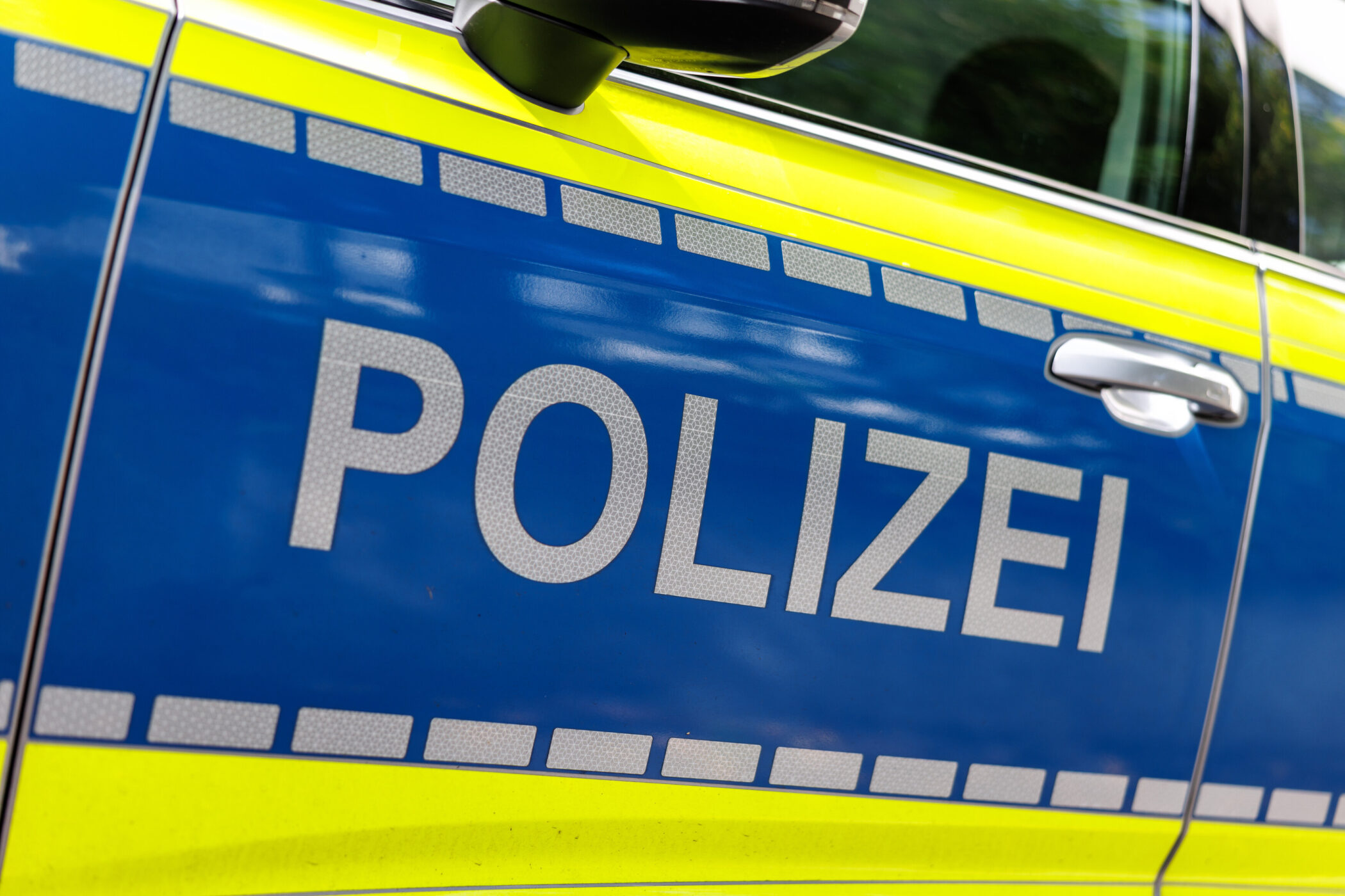 Blau-gelbes Polizeiauto mit Schriftzug "POLIZEI" auf der Tür.