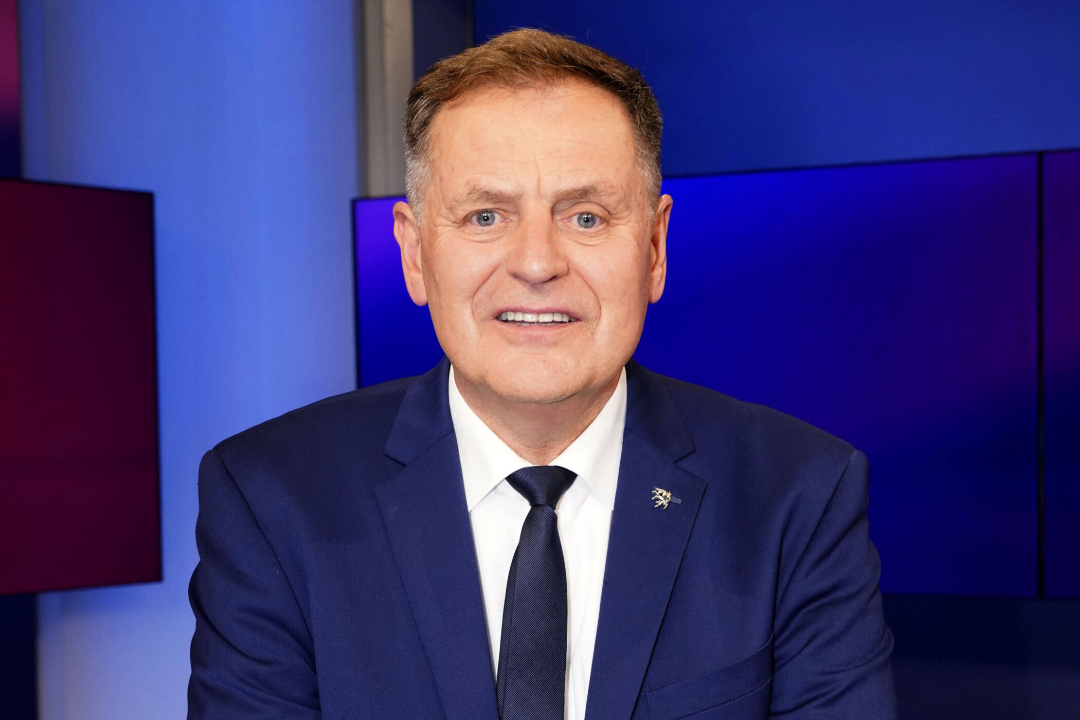 Mann im Anzug vor blauem Hintergrund.