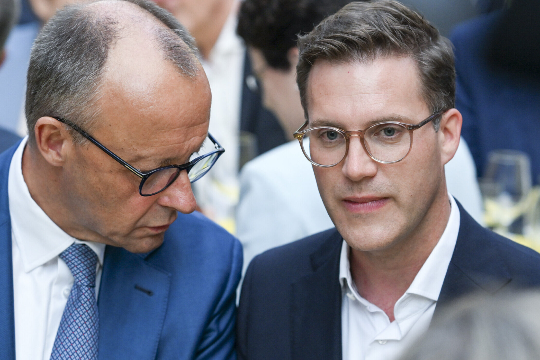 Zwei Männer in Anzügen, einer spricht zum anderen.