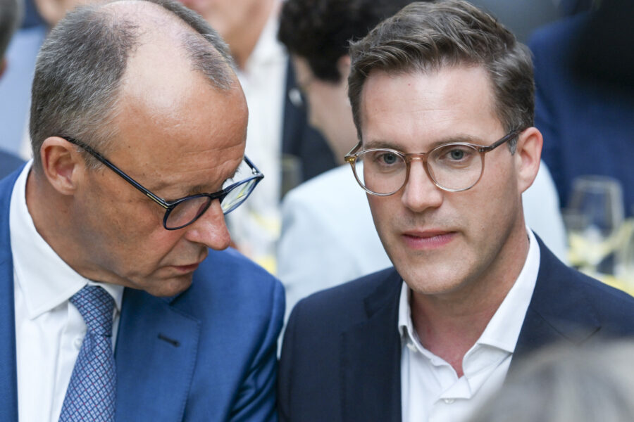 Zwei Männer in Anzügen, einer spricht zum anderen.