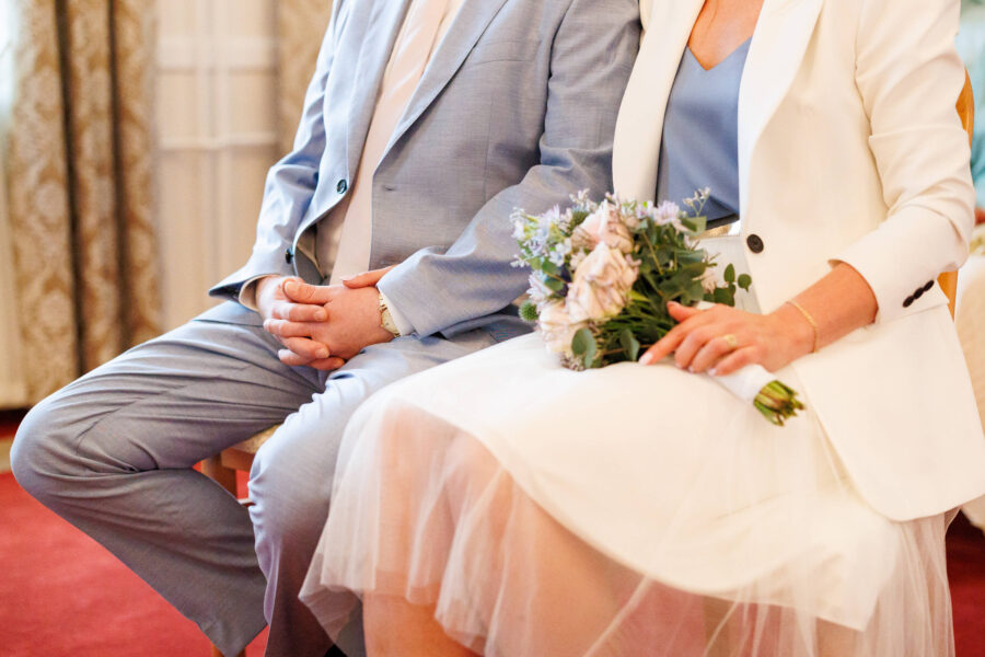 Zwei Personen in eleganter Kleidung, eine hält einen Blumenstrauß.