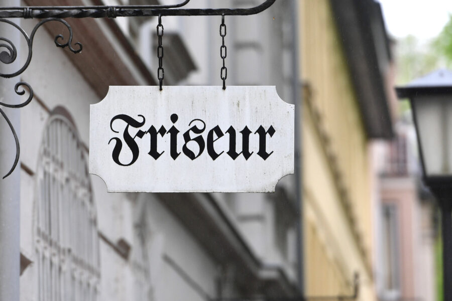Schild mit der Aufschrift "Friseur" in schwarzer Schrift.