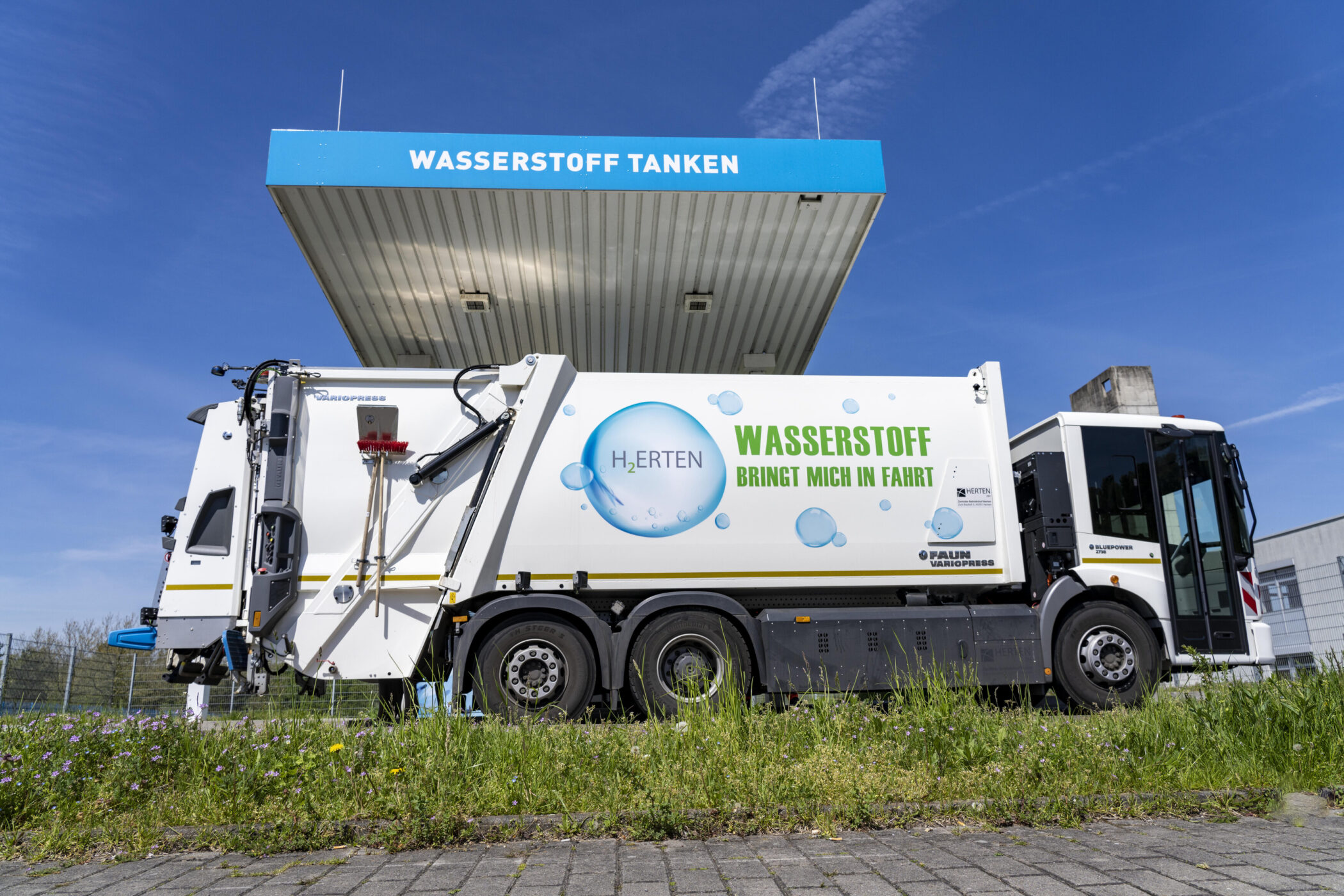 Müllwagen an Wasserstofftankstelle, Aufschrift: "Wasserstoff bringt mich in Fahrt".