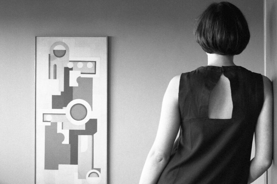 Person von hinten, schaut auf abstraktes Gemälde an der Wand.