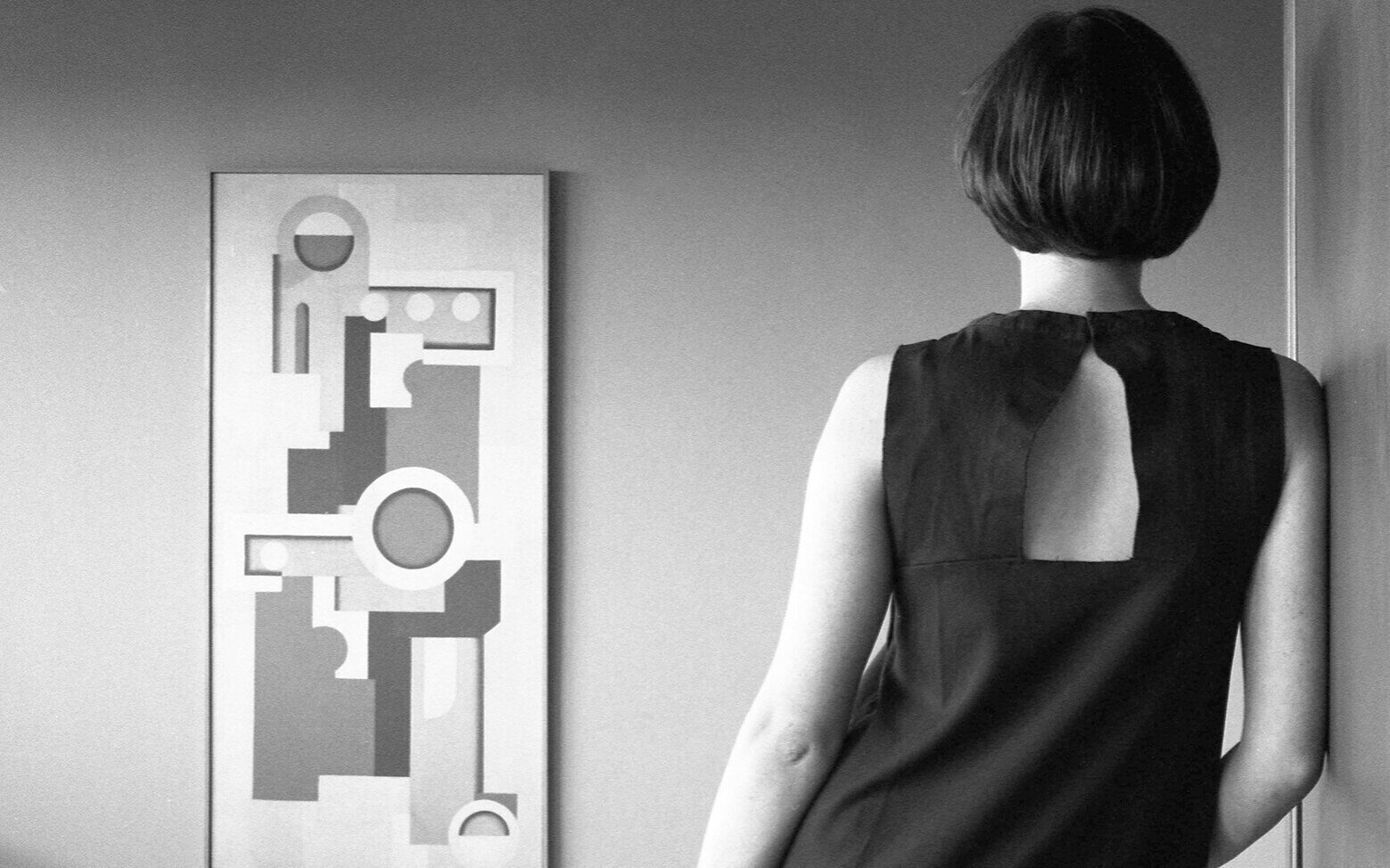 Person von hinten, schaut auf abstraktes Gemälde an der Wand.