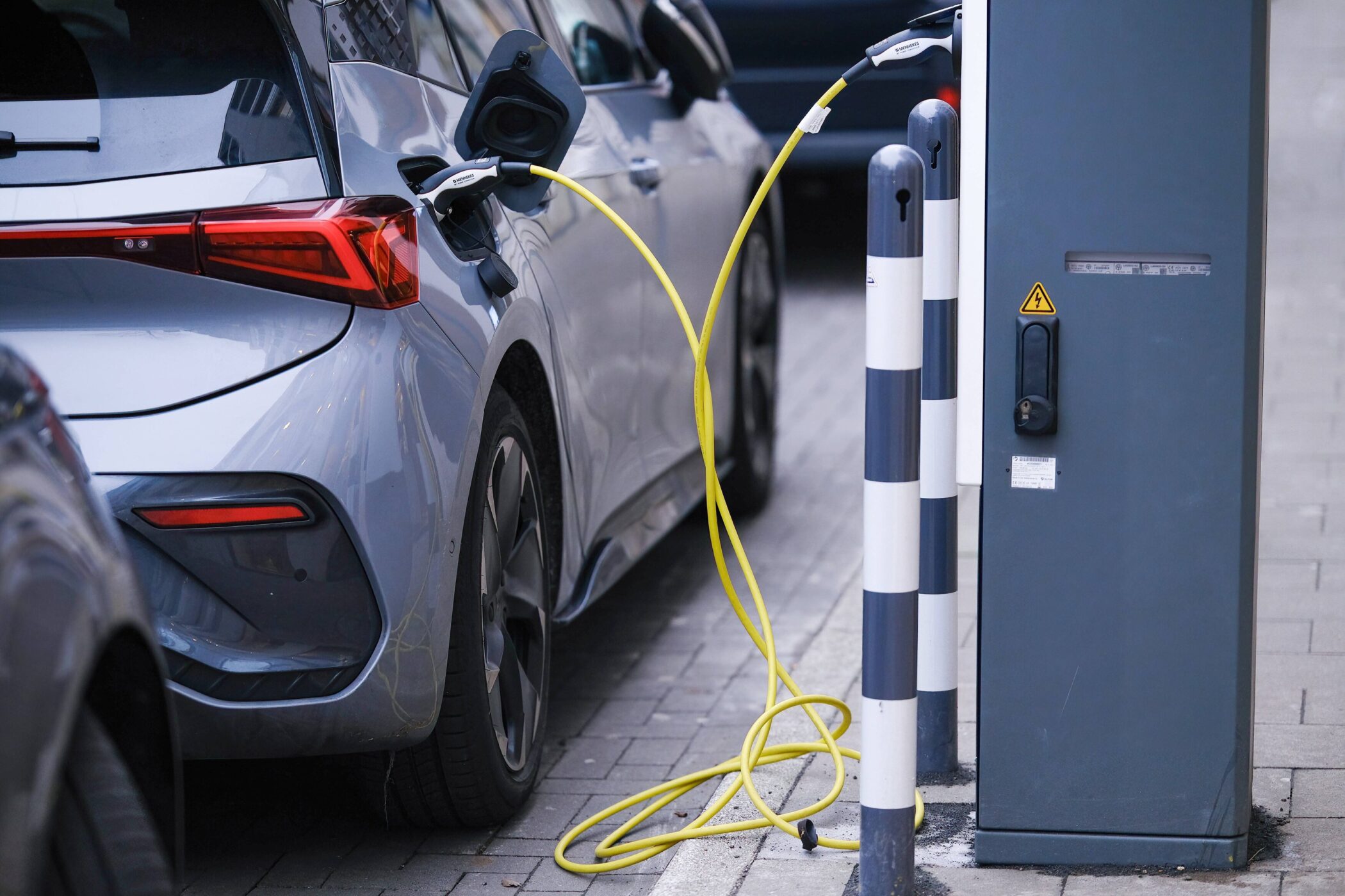 Auto lädt an Ladestation mit gelbem Kabel auf.