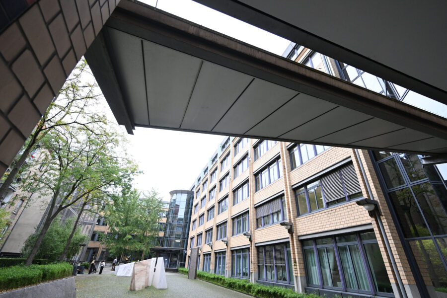 Gebäude mit Glasfassade und Bäumen im Innenhof, überdachter Durchgang.