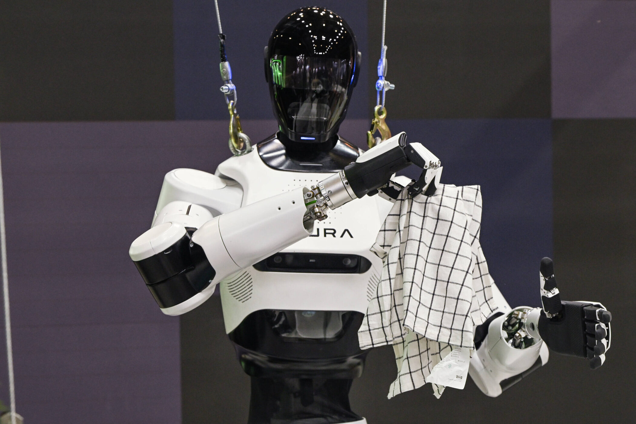 Roboter hält ein kariertes Tuch, mit Seilen befestigt.