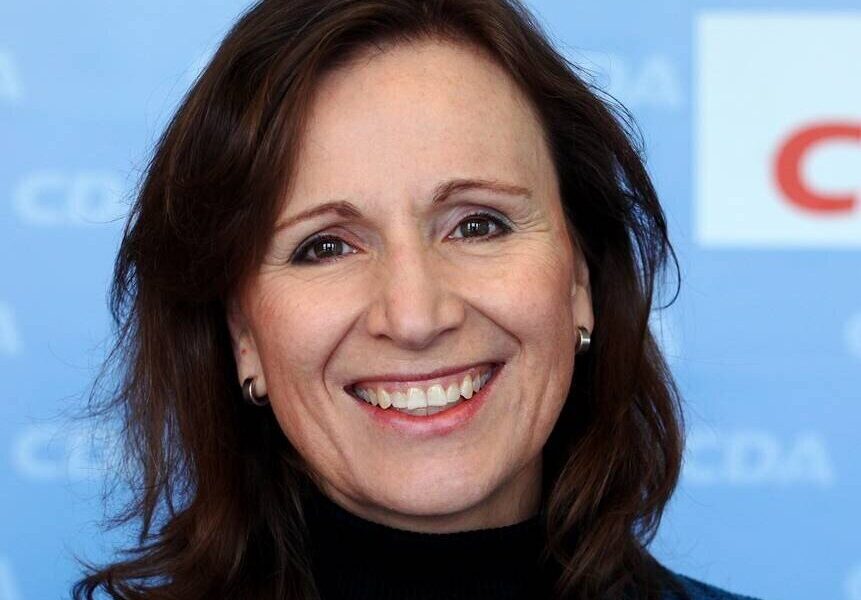 Frau lächelt vor blauem Hintergrund mit CDA-Logo.