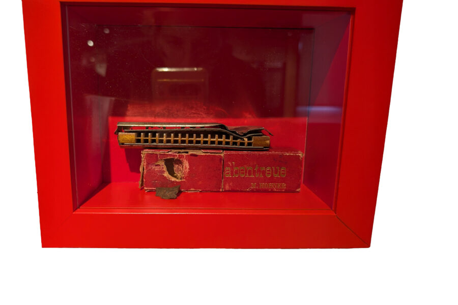 Rote Box mit Mundharmonika und abgenutzter Verpackung.