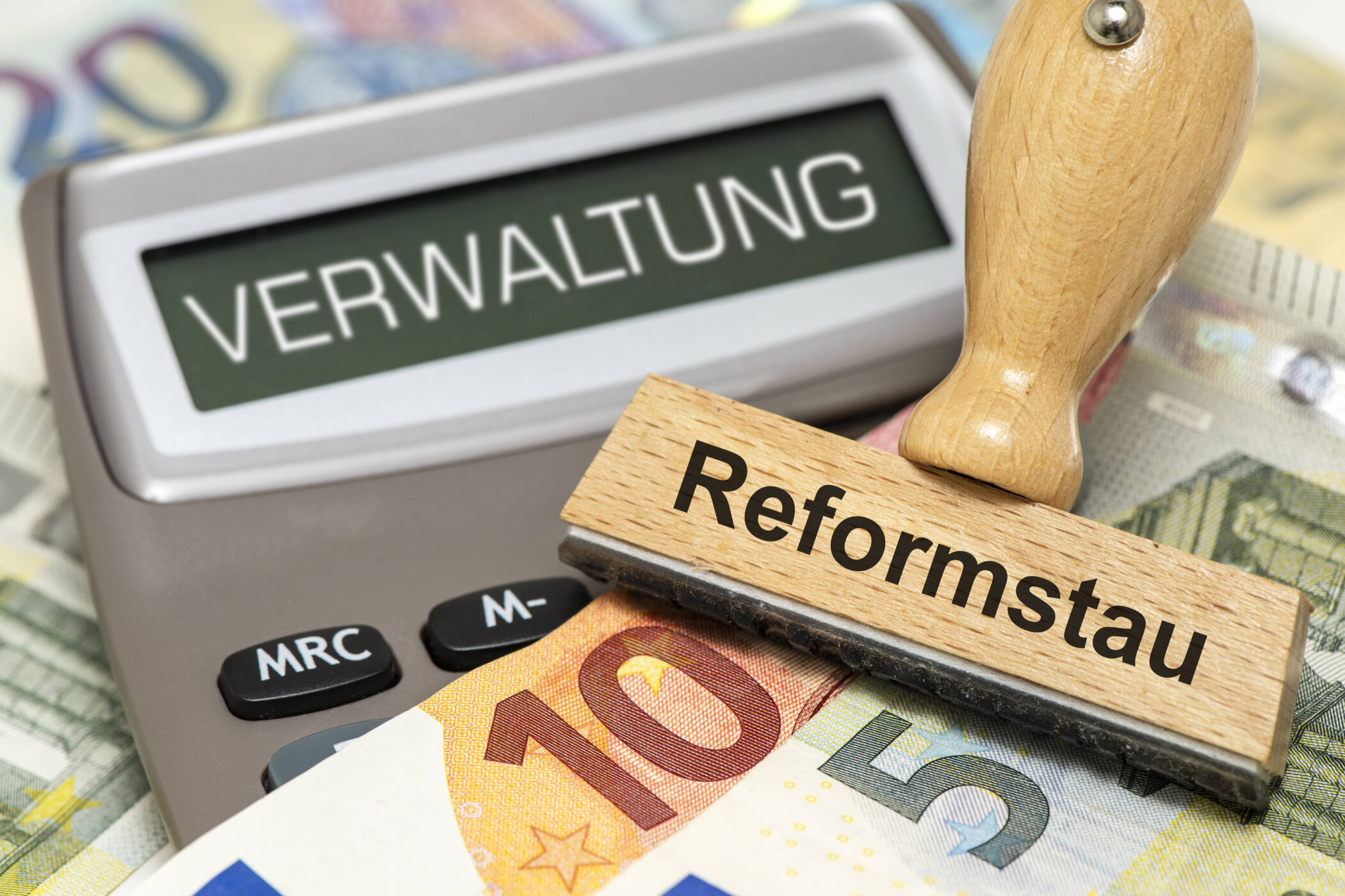 Taschenrechner mit "VERWALTUNG", Stempel "Reformstau", Euro-Geldscheine.