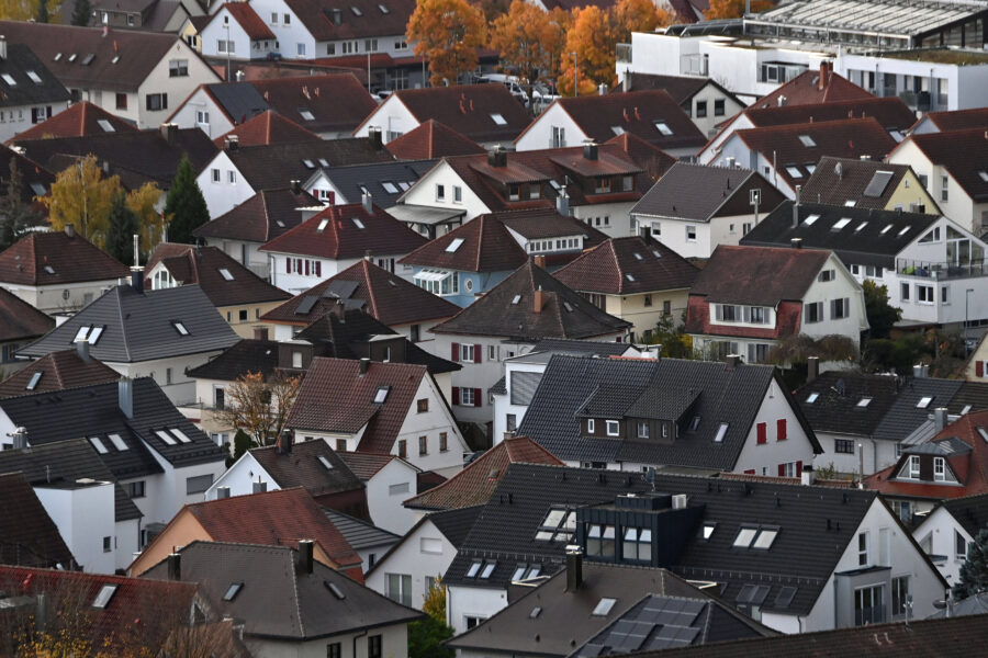 Dicht bebaute Wohnsiedlung mit Häusern und roten Dächern, Bäume im Hintergrund.