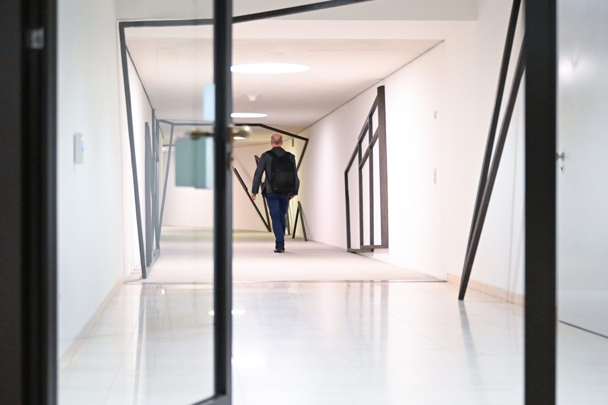 Person geht durch einen modernen Flur mit schrägen Wänden.