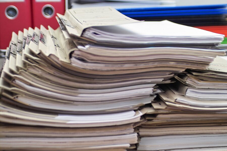 Stapel von Aktenordnern und Papierdokumenten auf einem Tisch.