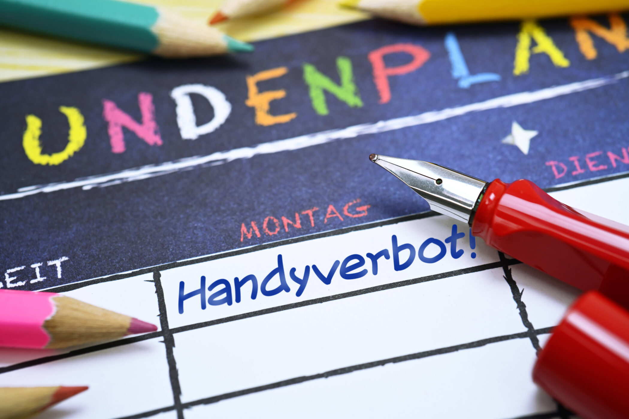 Stundenplan mit Stift und Buntstiften, Text: "Handyverbot!" am Montag.