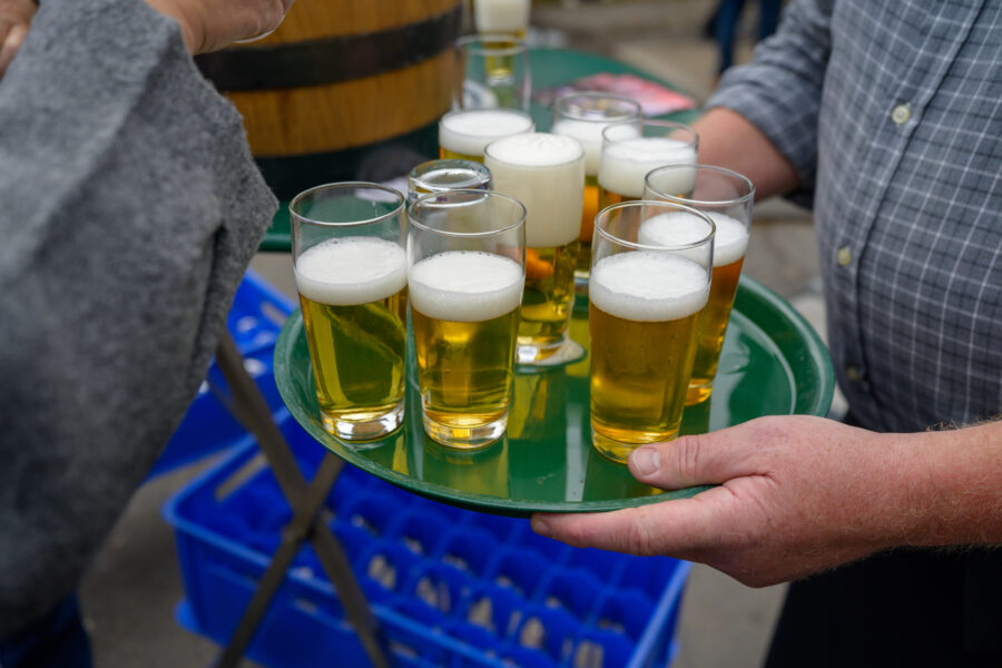 Tablett mit mehreren Gläsern Bier, von einer Person gehalten.