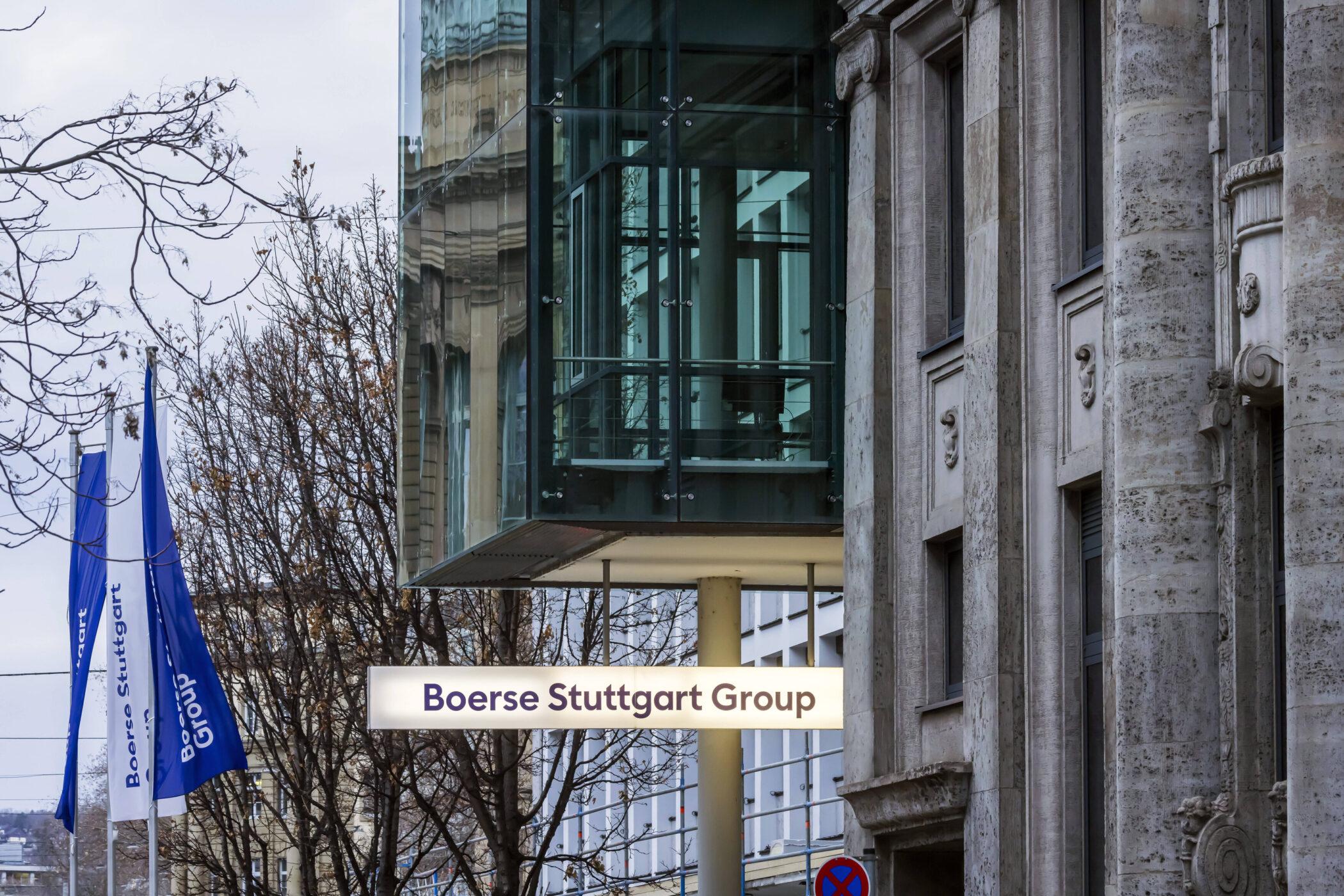 Gebäude mit Glasfassade, Schild "Boerse Stuttgart Group", zwei blaue Fahnen.