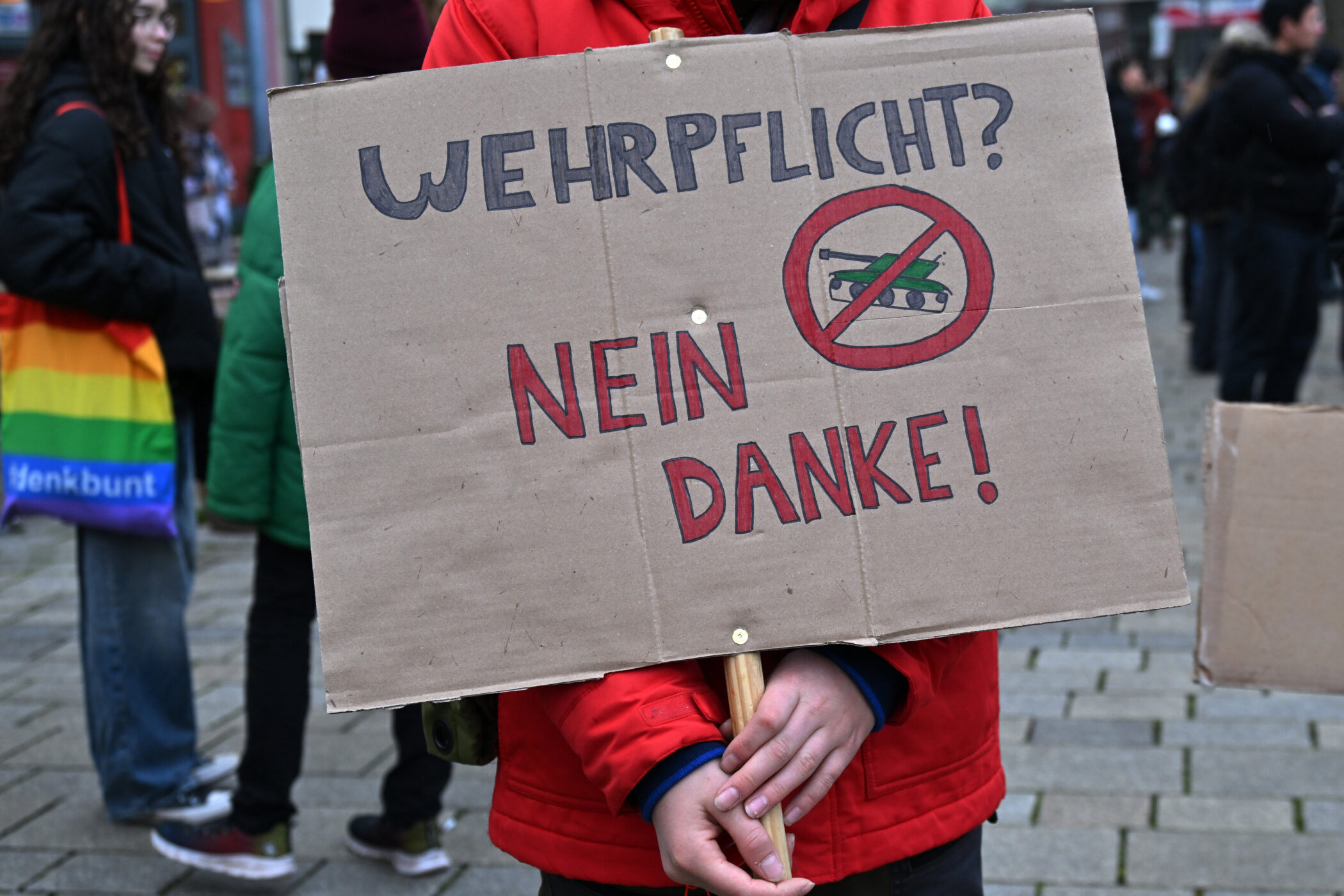 Person hält Schild mit Aufschrift "Wehrpflicht? Nein danke!" und durchgestrichenem Panzer.