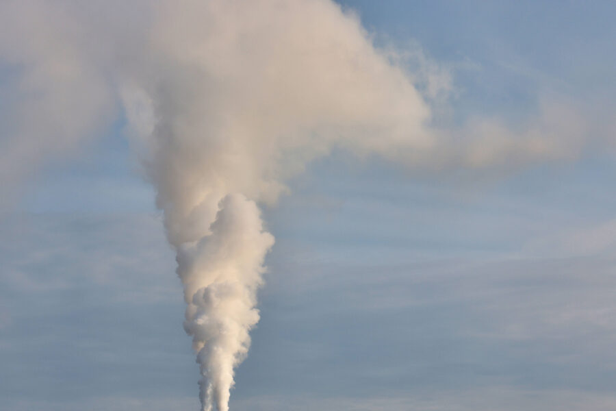 Rauchwolke steigt in den blauen Himmel auf.
