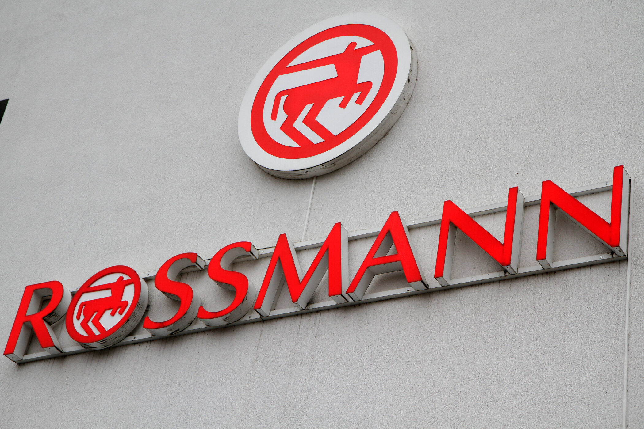 Rotes Rossmann-Logo und Schriftzug auf weißer Wand.