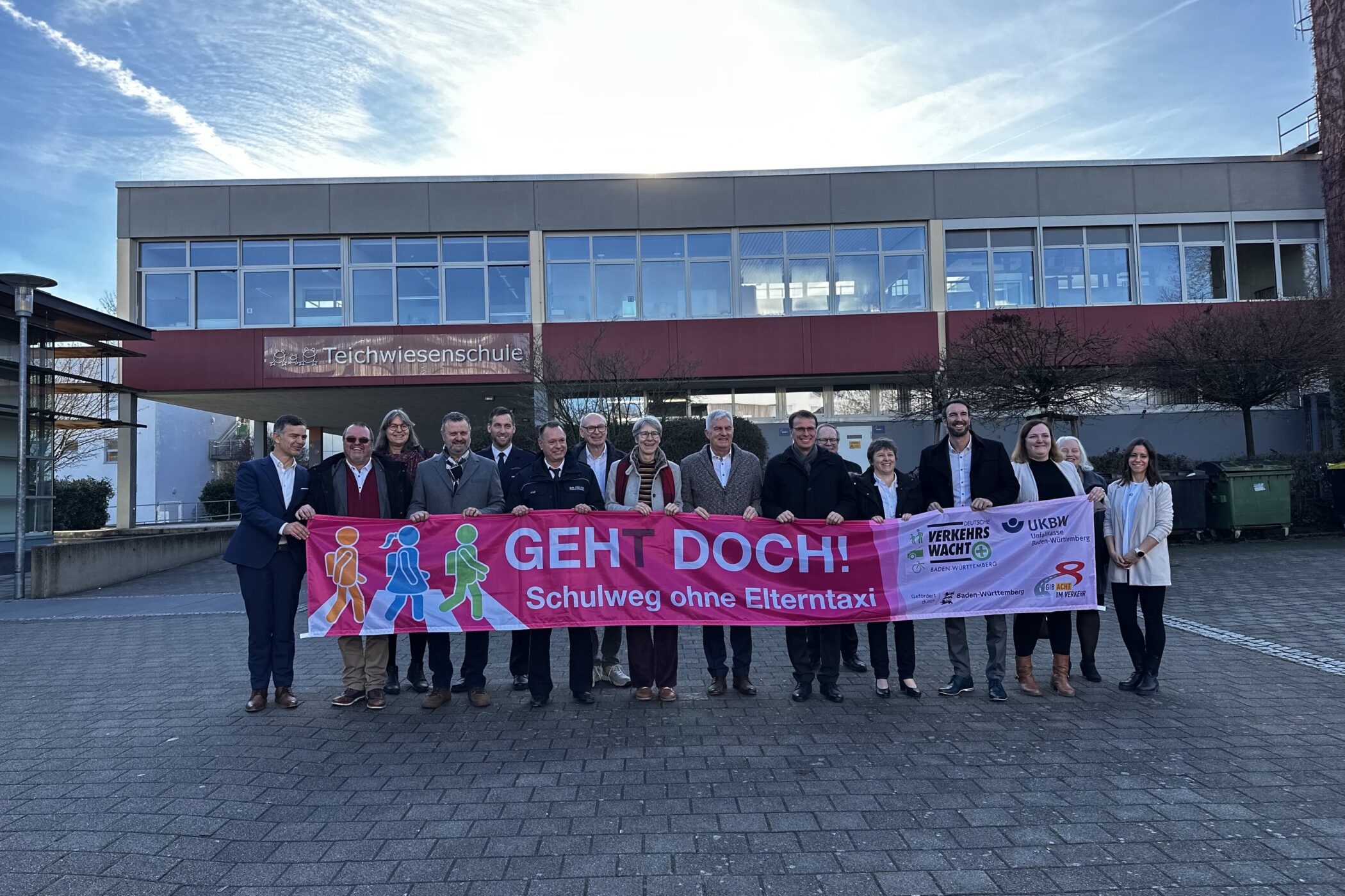 14 Personen halten ein Banner mit der Aufschrift "GEHT DOCH! Schulweg ohne Elterntaxi".