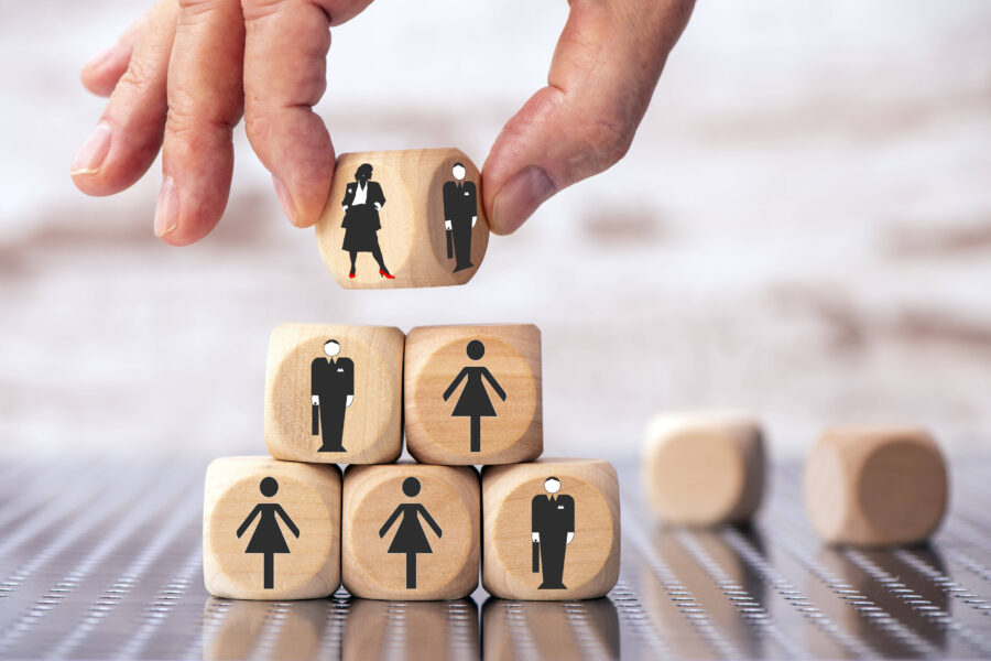 Hand stapelt Würfel mit Symbolen von Männern und Frauen.