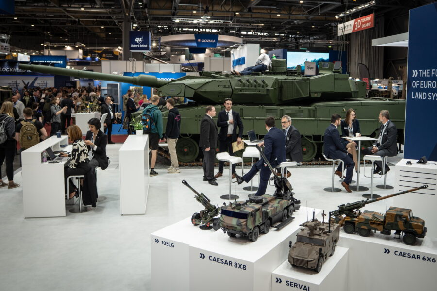 Menschen auf einer Messe, Panzer und Modelle im Hintergrund.