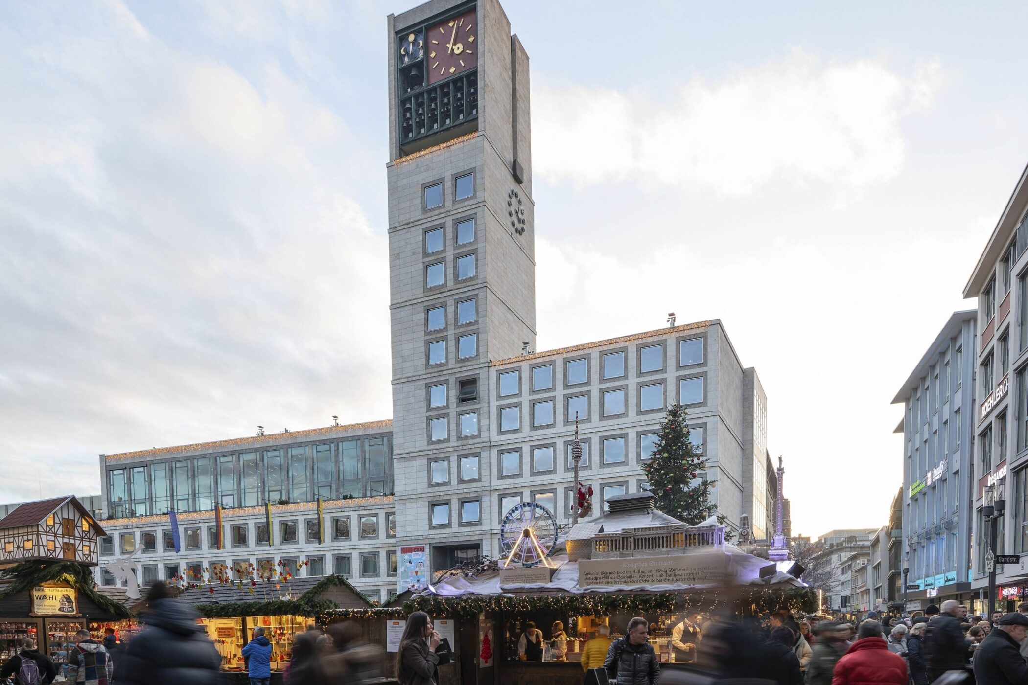 Menschen auf einem Weihnachtsmarkt vor einem Gebäude mit Uhrturm.