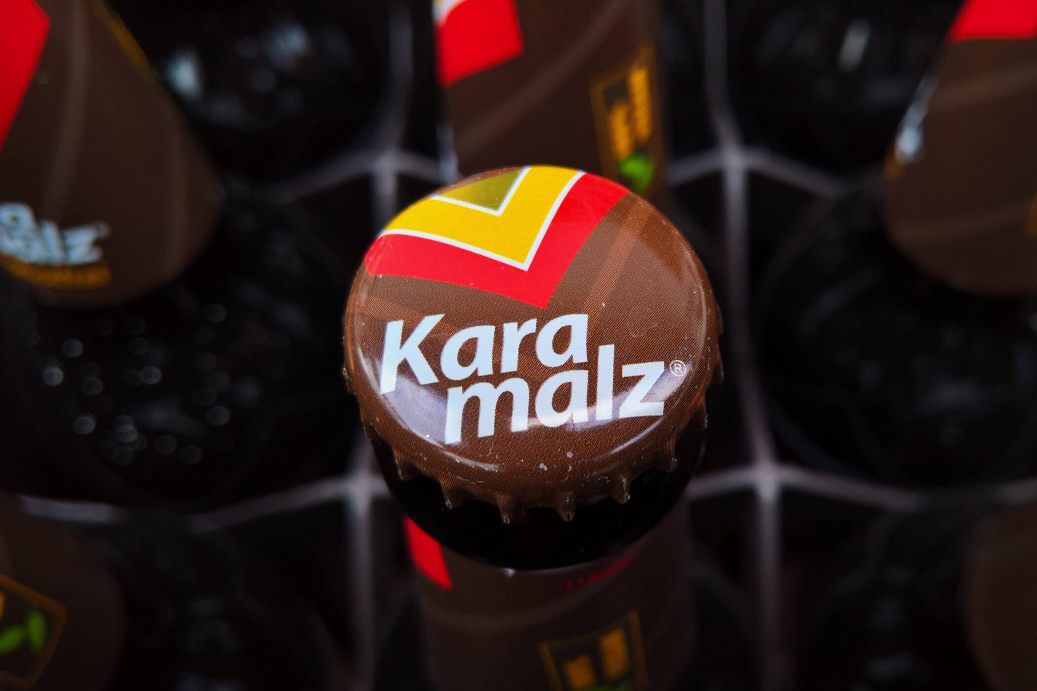 Brauner Kronkorken mit "Karamalz"-Schriftzug und buntem Logo.