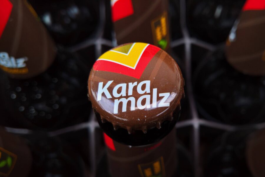 Brauner Kronkorken mit "Karamalz"-Schriftzug und buntem Logo.