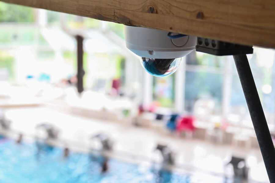 Überwachungskamera im Innenbereich, unscharfer Pool im Hintergrund.