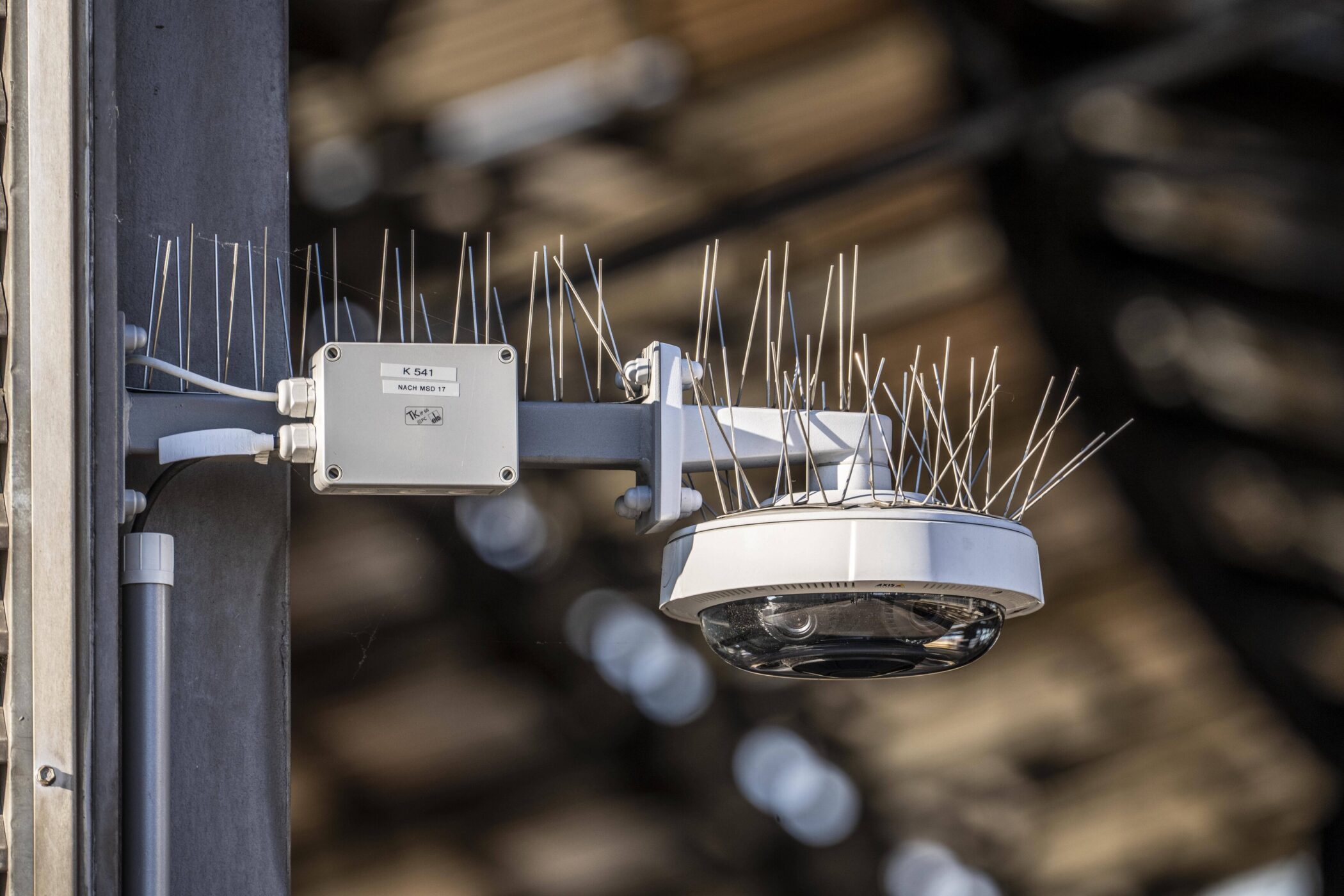 Überwachungskamera mit Spikes auf einem Metallarm montiert.