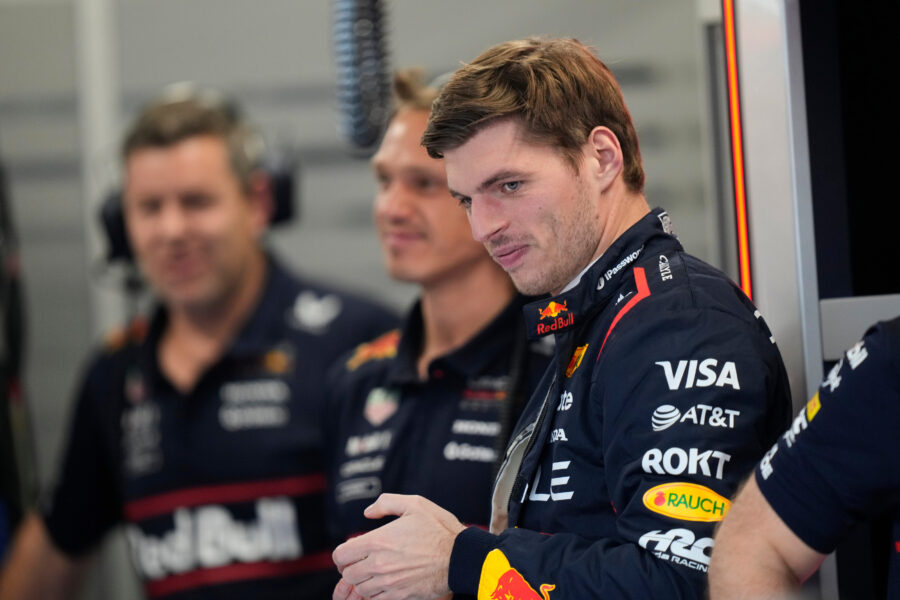 Drei Männer in Rennanzügen, einer im Vordergrund, zwei unscharf im Hintergrund.