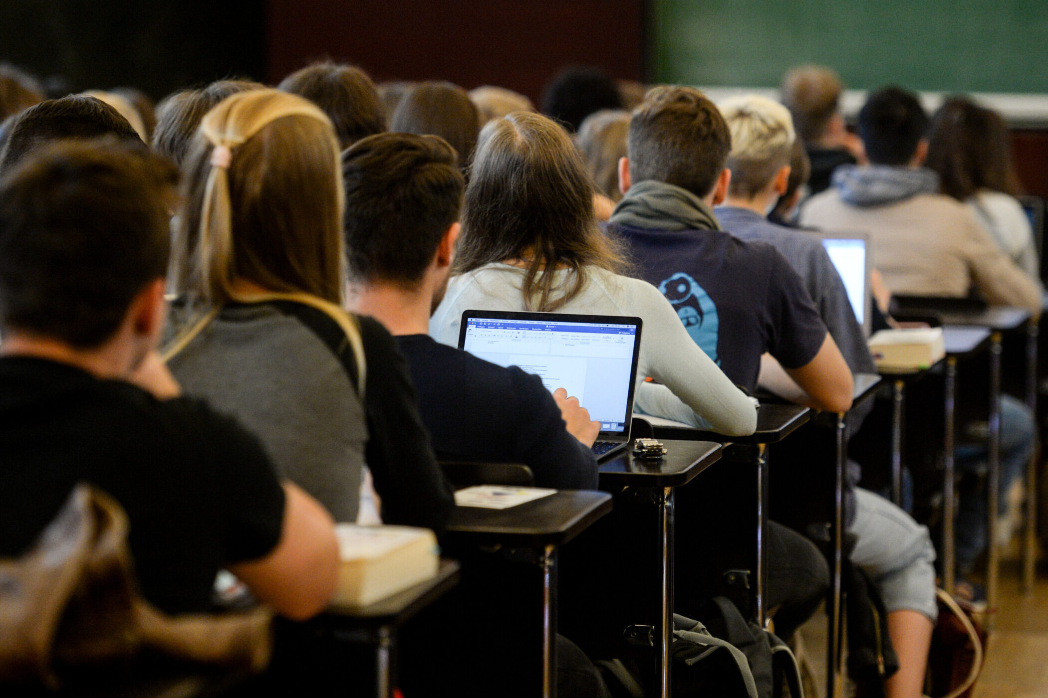 Mehrere Personen sitzen in einem Hörsaal und arbeiten an Laptops.