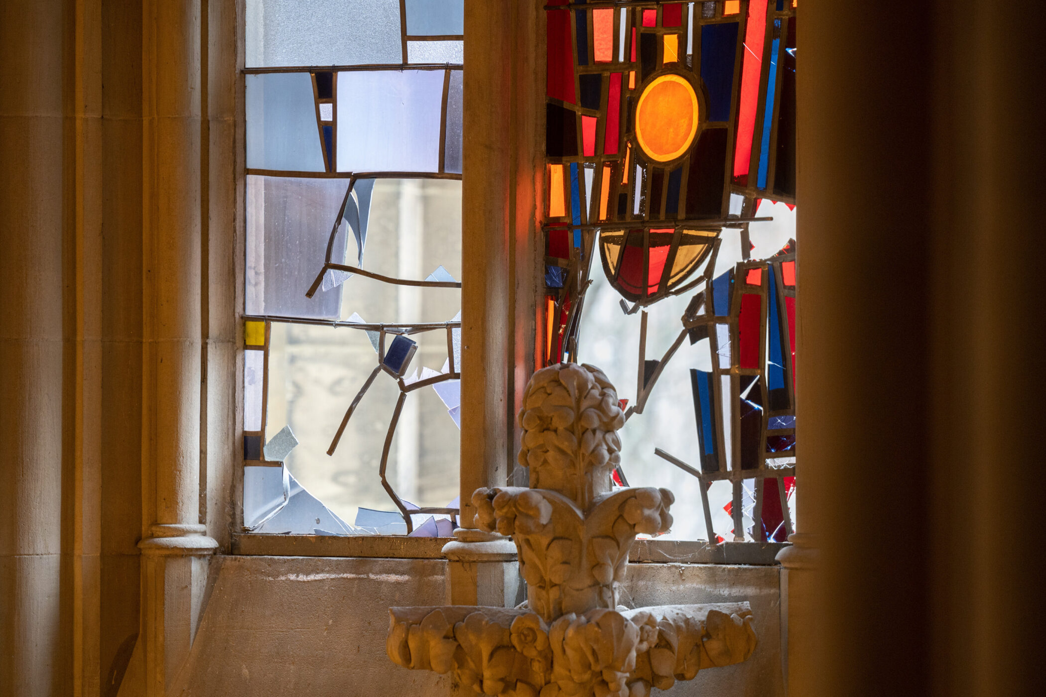 Buntglasfenster mit abstrakten Mustern in Blau, Rot und Orange, steinerne Verzierung.