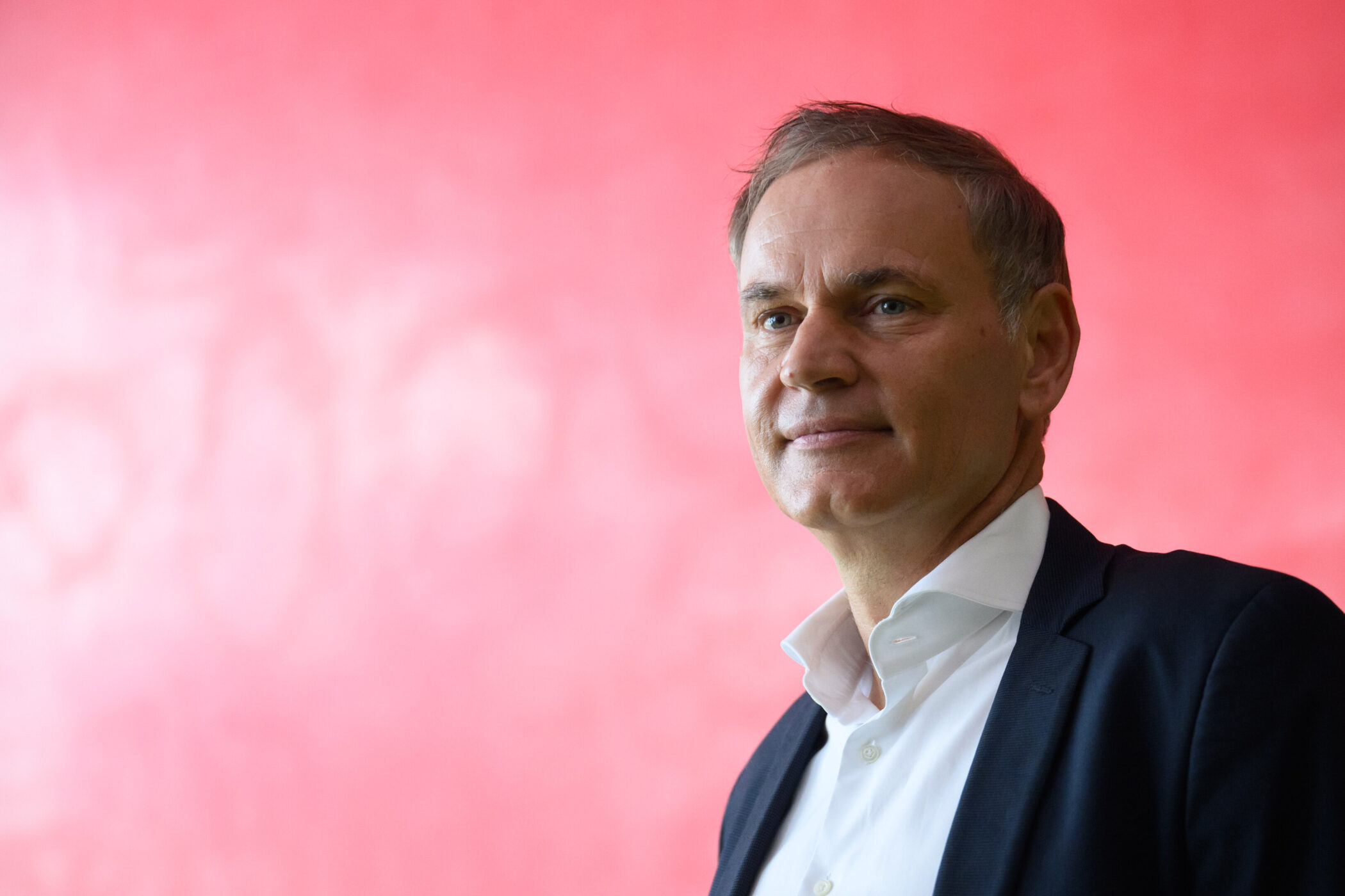 Mann im Anzug vor rotem Hintergrund.