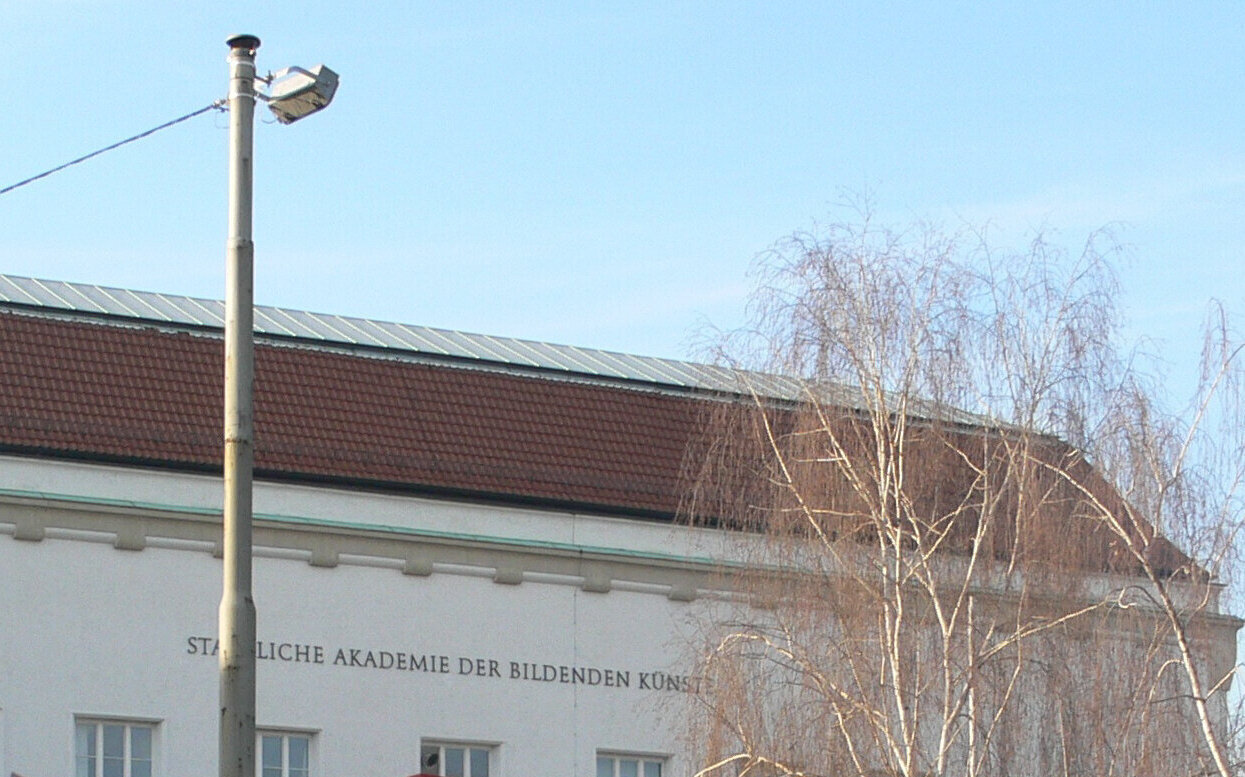 Gebäude mit Schriftzug "STAATLICHE AKADEMIE DER BILDENDEN KÜNSTE", Baum im Vordergrund.